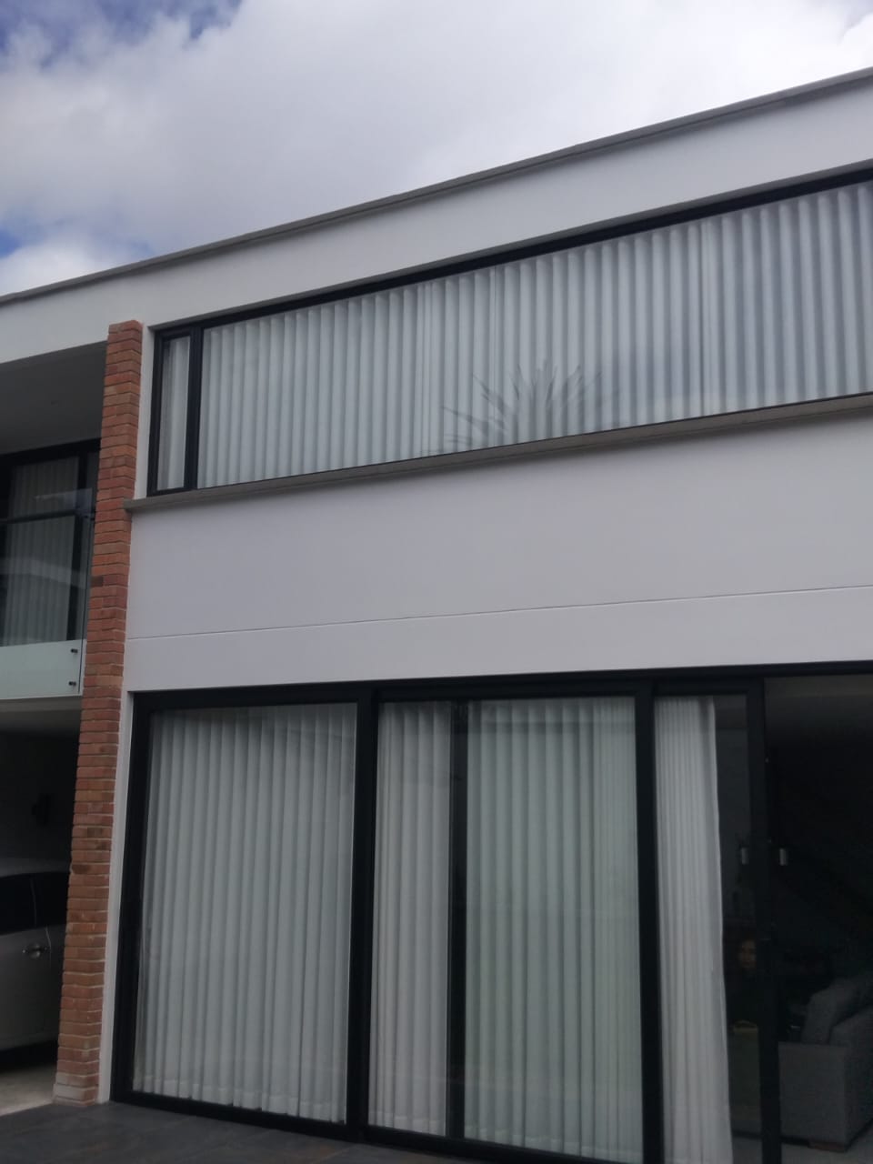 Fachada con ventanal alto y puertas corredizas con cortinas