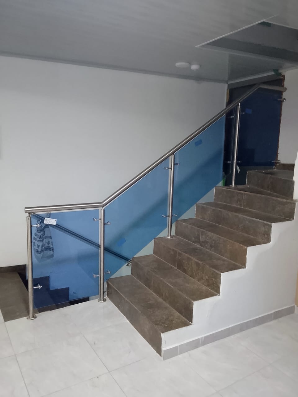 Escalera interior con baranda de vidrio azul y acero inoxidable